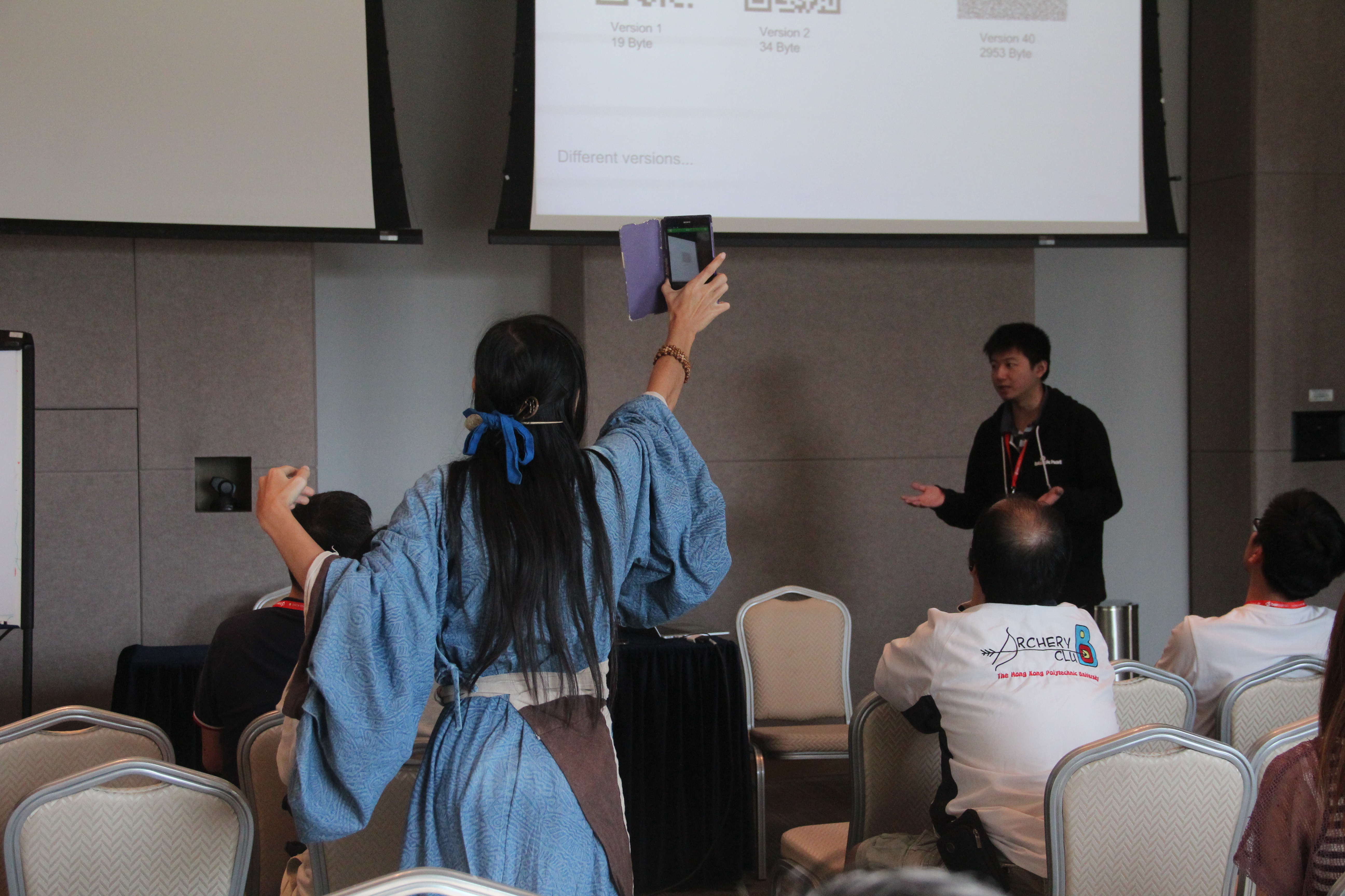 An audience dressed up in traditional Chinese attire taking photo of the QRCode demonstrated by Hu Pili